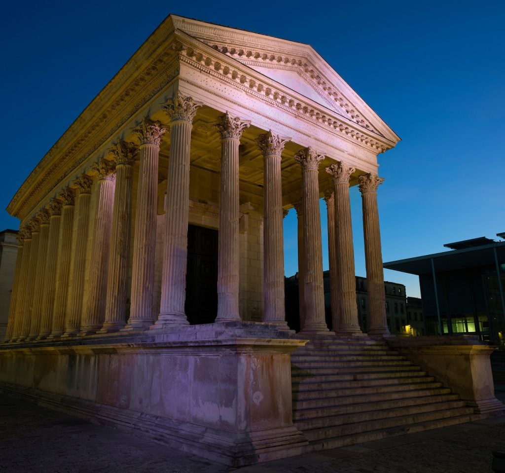 Ancient Roman temple with tall columns and a triangular pediment, illuminated at dusk like the grandeur a mandamus lawyer might admire, with steps leading to the majestic entrance.