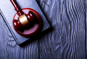 A judge’s gavel rests on a closed book atop a dark wooden surface, symbolizing the authority of the court and the dedication of every mandamus lawyer.