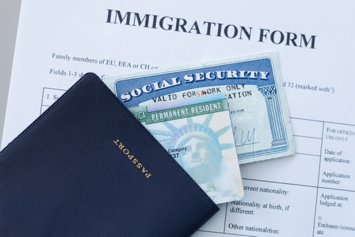 A passport, Social Security card, and green card placed on top of an immigration form—a scene often encountered by a mandamus lawyer handling delayed immigration cases.